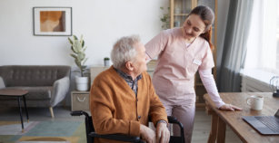 Portrait of smiling female nurse helping senior man in wheelchair