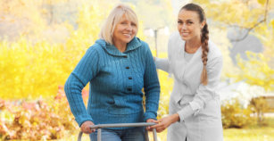 Senior woman with walking frame and young nurse in park