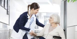 Physiotherapist Consoling Senior Woman Sitting In Wheelchair