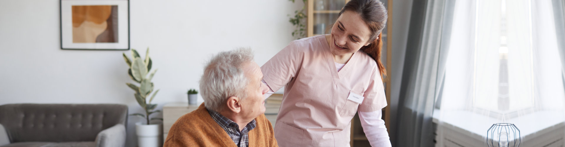 smiling female nurse helping senior man in wheelchair