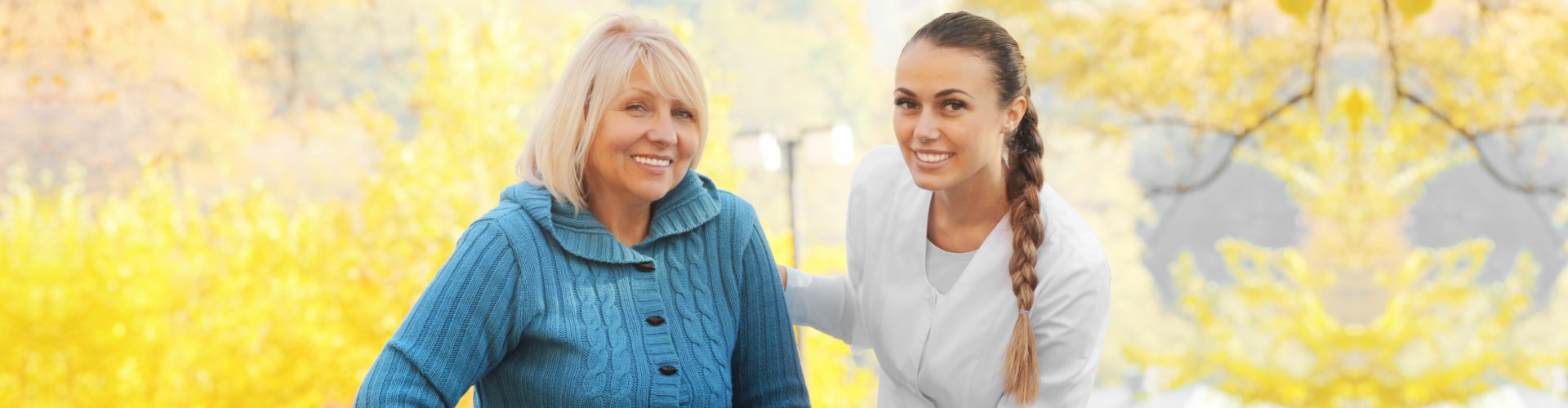 Senior woman with walking frame and young nurse in park