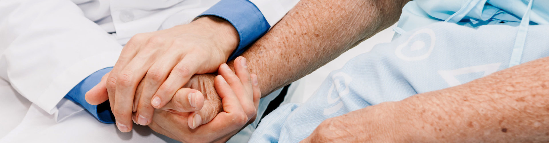 Doctor holding elderly person hand with care in hospital.